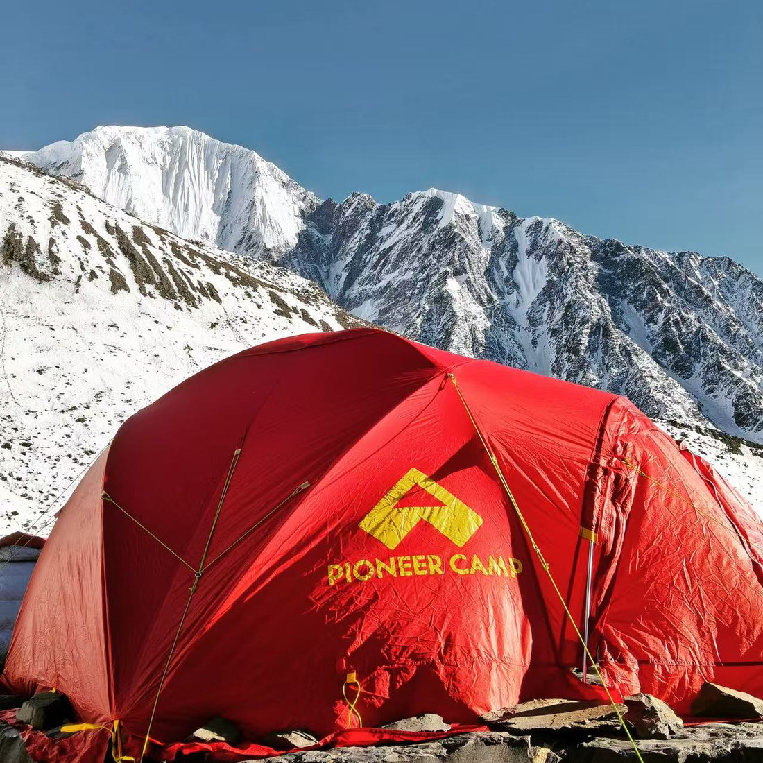 Red Pioneer Camp tent in front of snow-capped mountains